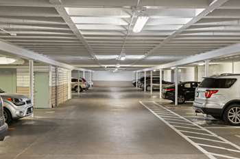 A parking garage with cars parked on both sides of the aisle.